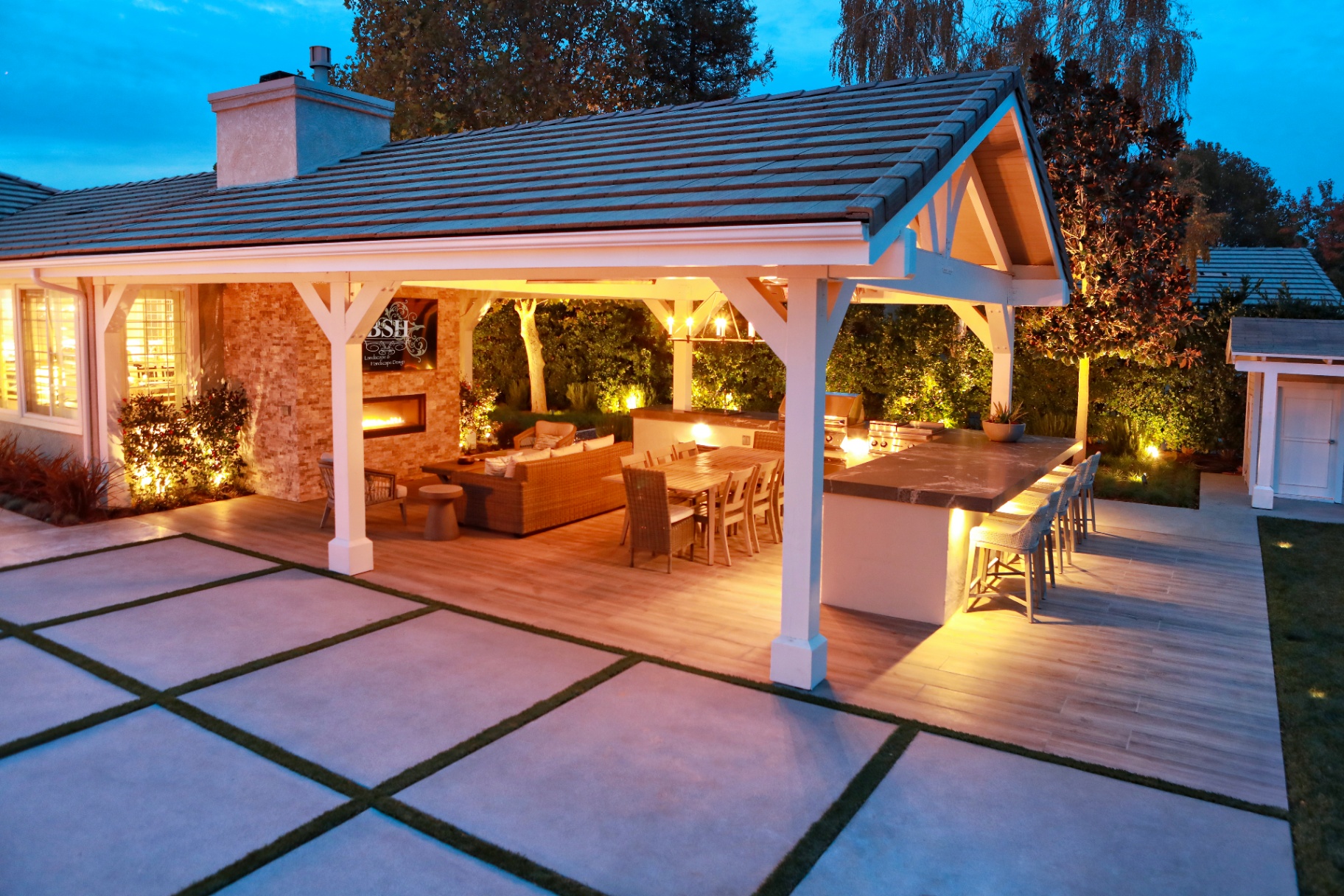 BSH Outdoor Living Spaces — illuminated gabled pavilion with dining and bar